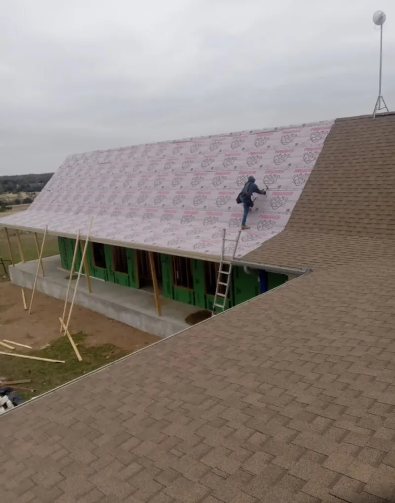 Worker preparing underlayment for a metal roof installation in Eidson Road